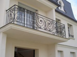 balcon-fier-forjat-cu-volute-pe-fatada-alba Balcon din fier forjat cu volute simple pe fațadă albă de clădire modernă